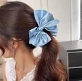 Detailansicht einer großen hellblauen Satin-Haarklammer mit Schleife am Pferdeschwanz - Ozeanblauer Bananen-Clip