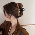 Detail view of a large amber acetate heart hair claw clip holding hair in place - Caramel color