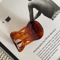 Dettaglio della molletta per capelli tartarugata ambra su una rivista di design - Stile Lucido / Tartarugato Lucido