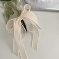 Detail of a beige ribbon bow banana clip with elegant wavy edges and a resin base hair accessory - Off-white