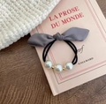 Dettaglio dell'elastico in raso grigio con perle eleganti e perline dorate su un libro - Grigio Viola