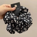 Detail of floral hair scrunchie in black with white patterns and cardboard packaging - Black Floral