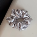Detalle de coletero de satén gris plateado con pedrería sobre fondo texturizado - Estilo Regular / Plateado