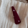 Dettaglio del fermaglio per capelli in feltro rosso a pois su tessuto beige - Triangolo Sottile Rosso