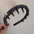 Dettaglio di un cerchietto in tessuto stile punk con borchie nere e una perla raffinata - Fascia con Etichetta Dorata Perla - Grigio Blu
