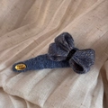 Dettaglio ravvicinato di un fermaglio per capelli in maglia blu con targhetta dorata - Fermagli laterali / Blu