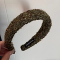 Makroaufnahme von Samt-Strickstirnband mit Pailletten, Goldfaden und handgemachtem Label - Grüne Serie Grober Tweed