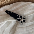 Detailansicht einer schwarzen Polka-Dot-Stoffklammer mit silberner Strassblumenverzierung - Schwarz Punktmuster Glänzender Strass Blume Clip