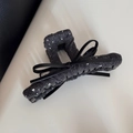 Détail d'une pince à cheveux en laine grise avec nœud en cuir noir et strass brillants - Pince droite