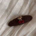 Dettaglio del fermaglio ciliegia in feltro con fiocco dorato e trama floccata rossa - Fermaglio Farfalla Ciliegia-Caffè Ovale
