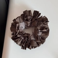 Macro detail of dark brown pleated hair scrunchie with satin texture on beige leather - Striped Pleated Edge - Coffee