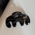Vue détaillée de la pince à cheveux en résine noire brillante avec logo doré - Style Arc / Noir