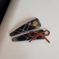 Dettaglio di fermagli per capelli a scacchi con targhetta dorata e fiocco in camoscio marrone - Coppia di Fermagli Quadri Neri Targhetta Dorata