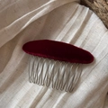 Detail van donkerrode fluwelen haar kam met 10 zilverkleurige metalen tanden op witte stof - Rood