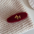 Dettaglio molletta per capelli in peluche rosso con cane dorato su maglione lavorato - Fermaglio Ovale in Lana Rossa Cavallo d'Oro