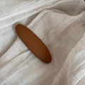 Detail of caramel fabric hair clip showing knit texture on natural linen background - Yellow Solid Oval Clip