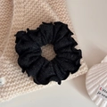 Close-up of a black pleated knit scrunchie with soft ruffled texture on a white backdrop - Black