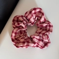 Detail showing the soft knitted texture and red houndstooth pattern of the scrunchie - Scrunchie / Pink Plaid