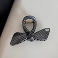 Detail showing faux carbon fiber weave texture and gold metal spring on the bow hair claw - Bow
