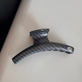 Detail of grey hair claw clip showing carbon fiber texture and silver Hand Made plaque - Linear