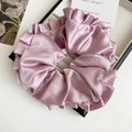 Détail d'un grand chouchou en satin rose avec texture en soie et plis élégants ondulés - Rose