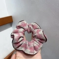 Pink and grey houndstooth hair scrunchie with brown trim being held by hand - Scrunchie