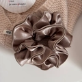 Macro shot of large champagne gold satin hair scrunchie with metallic shimmer and ruffles - Champagne