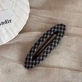 Dettaglio di un fermaglio per capelli a goccia in tessuto a scacchi blu e beige su stoffa - Ovale Traforato (Quadretti Neri)