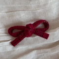 Close-up of red plaid tweed bow hair clip with detailed woven fabric texture on linen - Bright Red