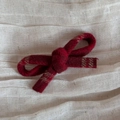 Macro shot of red wool bow hair clip with textured fabric on soft linen background - Dark Red