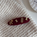 Macro detail of red velvet hair clip with golden horse and money bag charms on knit background - Oval Style (Lucky Horse)
