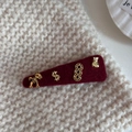 Detail of red velvet hair clip with golden horse and money charms on knit fabric - Triangle Style (Lucky Horse)