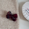 Détail de la pince à cheveux noeud en laine rouge sur fond de tricot beige doux - Carreaux Rouge Et Gris