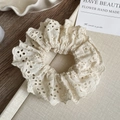 Detail van gebroken witte haarelastiek met geborduurd kant en bloemmotieven - Beige