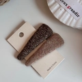 Dettaglio di fermagli per capelli BB in tweed marrone e viola su un cartoncino bianco - Triangolo / Marrone