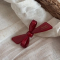 Close-up of a glossy burgundy ribbon hair clip with gold lettering on a rustic fabric - Slender Ribbon Design (New Year Red-Slender Bow Clip) / Festive Red - Slender Bow Clip