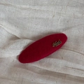Detail einer roten Filz-Haarklammer mit goldenem Handmade-Schriftzug auf Leinenstoff - Roter Ovaler Gold-Label-Stil