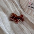 Close-up of brown acetate horse charm hair tie on elegant fabric with sea shell - Coffee Horse (Hair Clip)