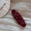 Detail of red knit hair clip with white embroidery on cream textured fabric - Red Oval Clip-Line Segment