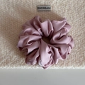 Détail d'un chouchou en satin rose poudré avec éclat soyeux sur fond beige pelucheux - Rose