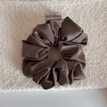 Vue détaillée d'un chouchou en satin marron foncé avec texture soyeuse sur fond en tissu - Marron