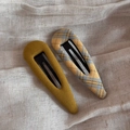 Close-up of mustard yellow and blue plaid fabric BB hair clips on a soft beige background - Hollow Teardrop