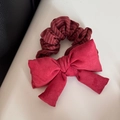 Dettaglio di elastico a righe rosse con un grande fiocco in camoscio su fondo bianco - Elastico per Capelli Imbottito a Righe
