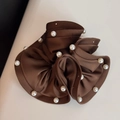 Detailed close-up of brown satin scrunchie featuring elegant white faux pearl edge accents - Brown