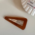 Primer plano de un pasador de pelo triangular de acetato ámbar con letras doradas - Marrón