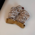 Dettaglio dell'elastico a scacchi con fiocco giallo e bottone marrone vintage - Elastico Fiocco a Quadretti Beige