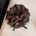 Dettaglio dell'elastico scrunchie marrone a righe con fiocco e ciondolo dorato - Stile Sciancrato / caffè