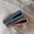Close-up of blue and plaid fabric-wrapped hair clips on a textured cream background - Blue Series Pair - Hollow Triangle