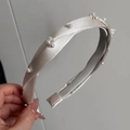 Dettaglio del cerchietto in raso champagne con nodo intrecciato e perle bianche eleganti - Bianco Sporco