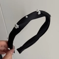 Dettaglio di un cerchietto intrecciato in raso nero con fiori in perle finte e decorazioni - Nero